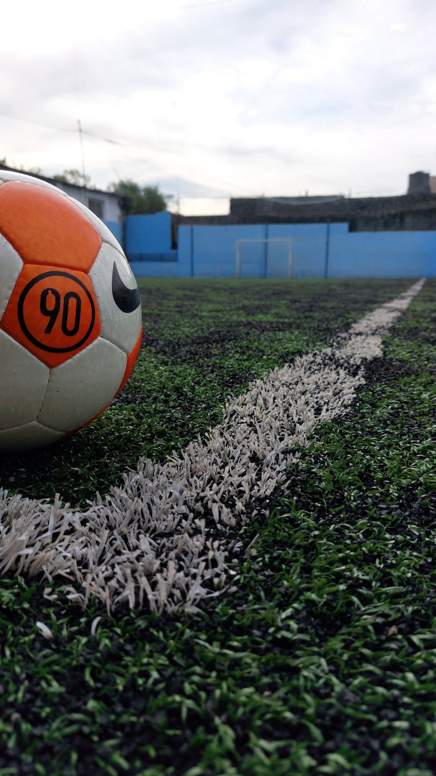 Pelota sobre el césped sintético de la cancha de fútbol