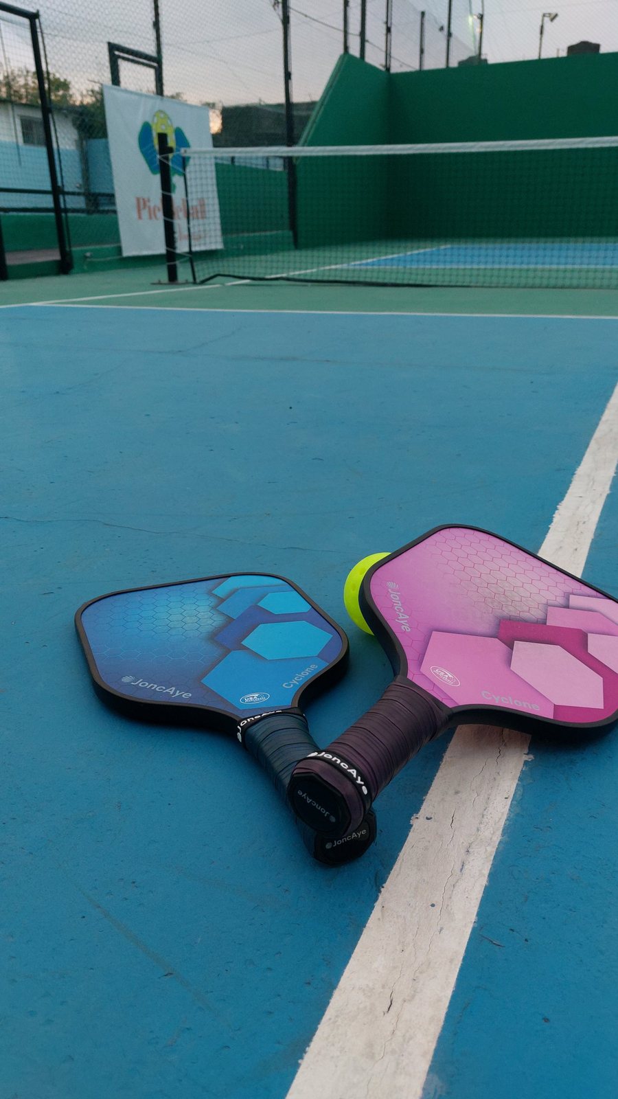 Paletas y pelota de pickleball sobre la cancha